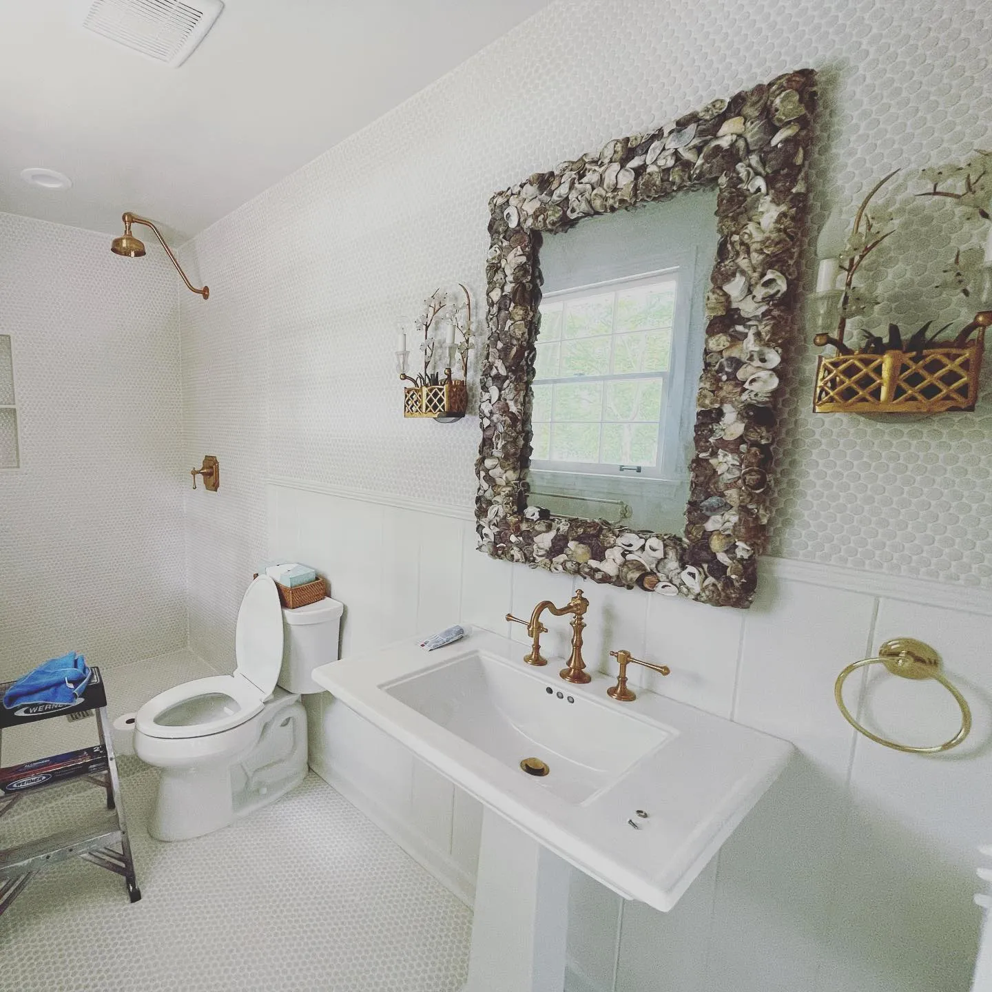 Remodeled bathroom with a shell mirror and pedestal sink