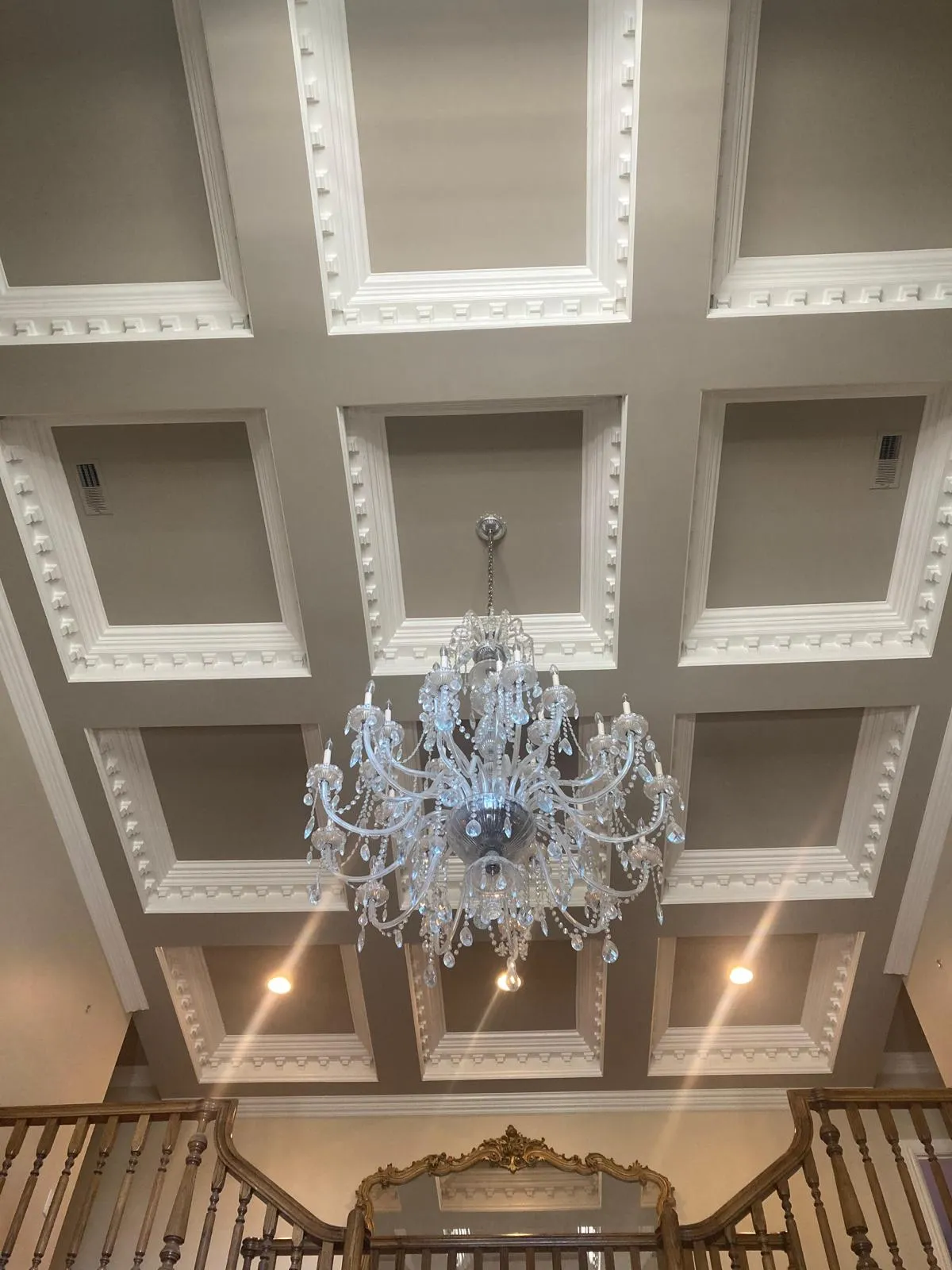 Coffered ceiling finished in white around a crystal chandelier